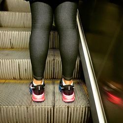 Low section of woman standing on escalator