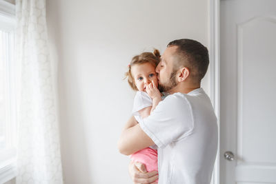 Side view of man kissing daughter at home