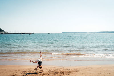 Man surfing on beach against clear sky