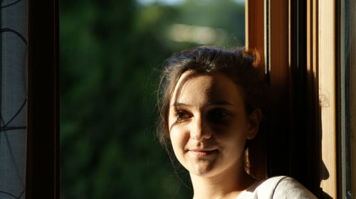 Close-up portrait of woman looking through window