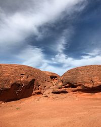 Rock formations in desert against cloudy sky