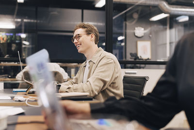 Happy businessman wearing eyeglasses sitting at desk working in office