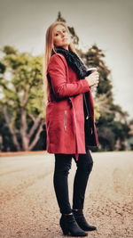 Full length of woman standing with red umbrella