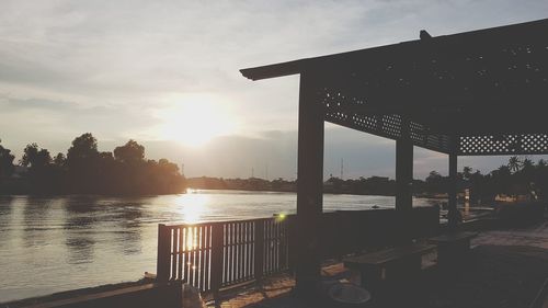 Silhouette bridge over river against sky during sunset