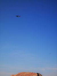 Low angle view of airplane in flight against blue sky