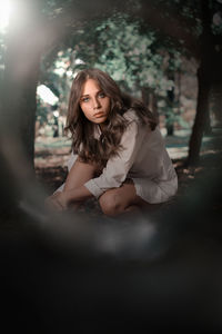 Portrait of beautiful young woman sitting in forest