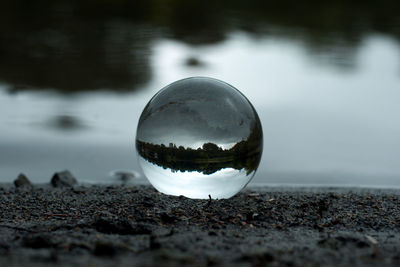 Close-up of crystal ball with reflection in lake