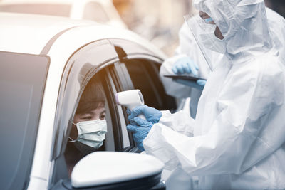 Healthcare worker making coronavirus test at car