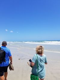 Rear view of men on beach against sky