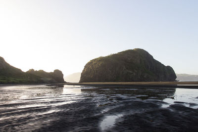 Rocks in sea against clear sky