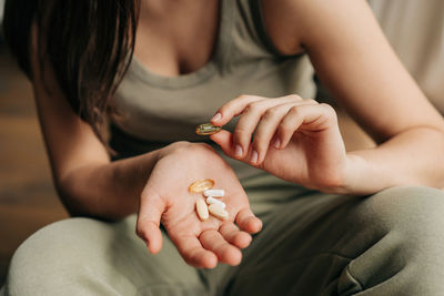 Closeup unrecognizable caucasian woman holding omega-3 fish oil capsules in hands and vitamins