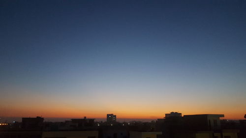 Silhouette cityscape against clear sky during sunset