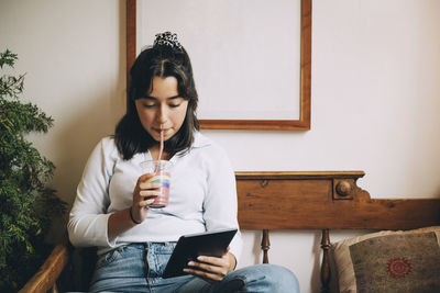 Young woman using mobile phone while sitting at home