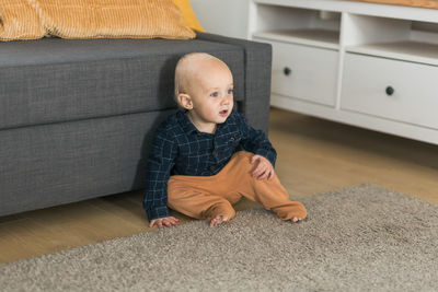 Portrait of cute boy sitting on sofa at home