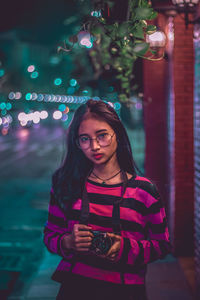 Portrait of woman standing in city at night