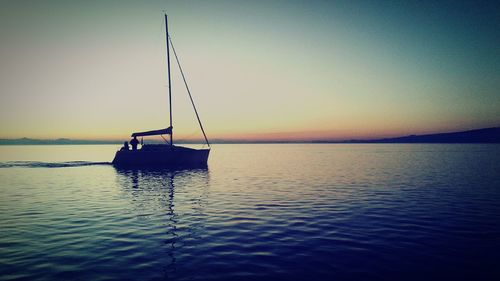 Silhouette man in sea against sky during sunset