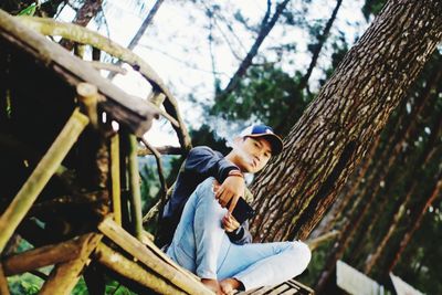 Side view of man looking away while sitting on tree
