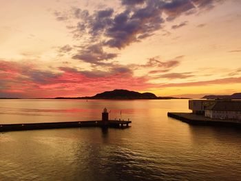 Golden hour over a harbor, aerial view, orange color sky, pier, lighthouse, island, seascape