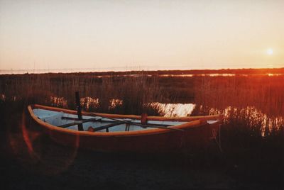 Boats moored in lake against clear sky during sunset