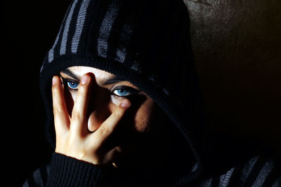 Close-up portrait of young woman covering face with hand