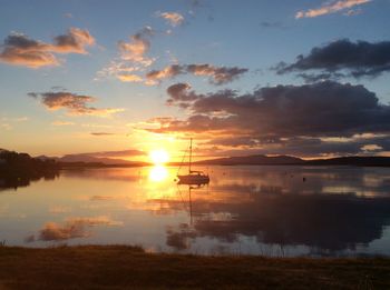 Scenic view of loch against sky during sunset