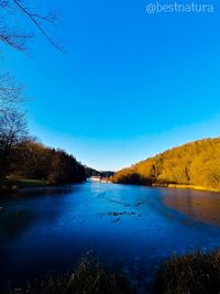 Scenic view of lake against clear blue sky