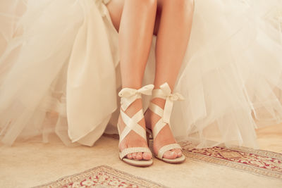 Low section of bride wearing sandals at home