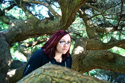 Thoughtful young woman with dyed hair by tree branches