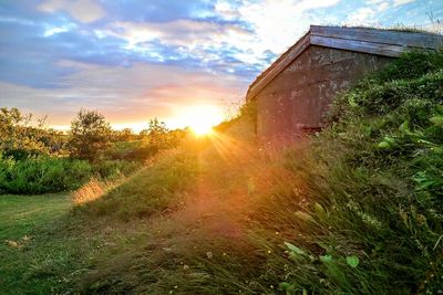 House on field against sky at sunset