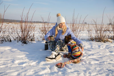 Rear view of man sitting on snow covered field