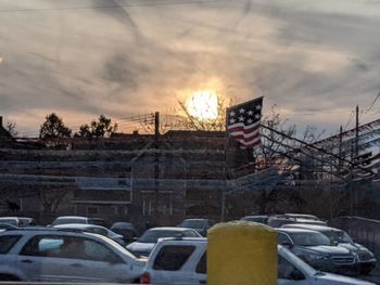 Cars in city against sky during sunset