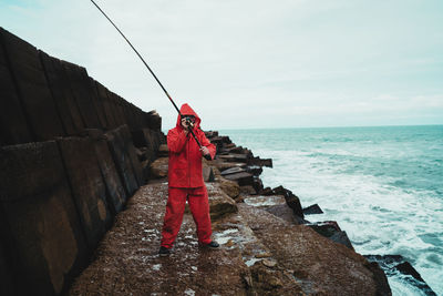 People standing on rock by sea against sky