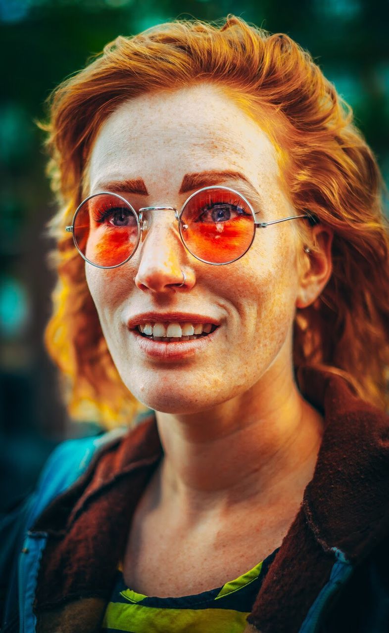 portrait, glasses, headshot, smiling, lifestyles, looking at camera, one person, front view, focus on foreground, real people, redhead, happiness, young adult, leisure activity, adult, sunglasses, close-up, eyeglasses, teeth, hairstyle, fashion, dyed red hair, beautiful woman