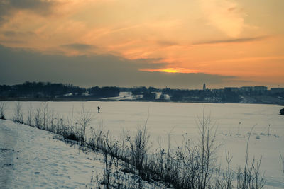 Scenic view of frozen field against sky during sunset