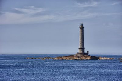 Lighthouse by sea against sky