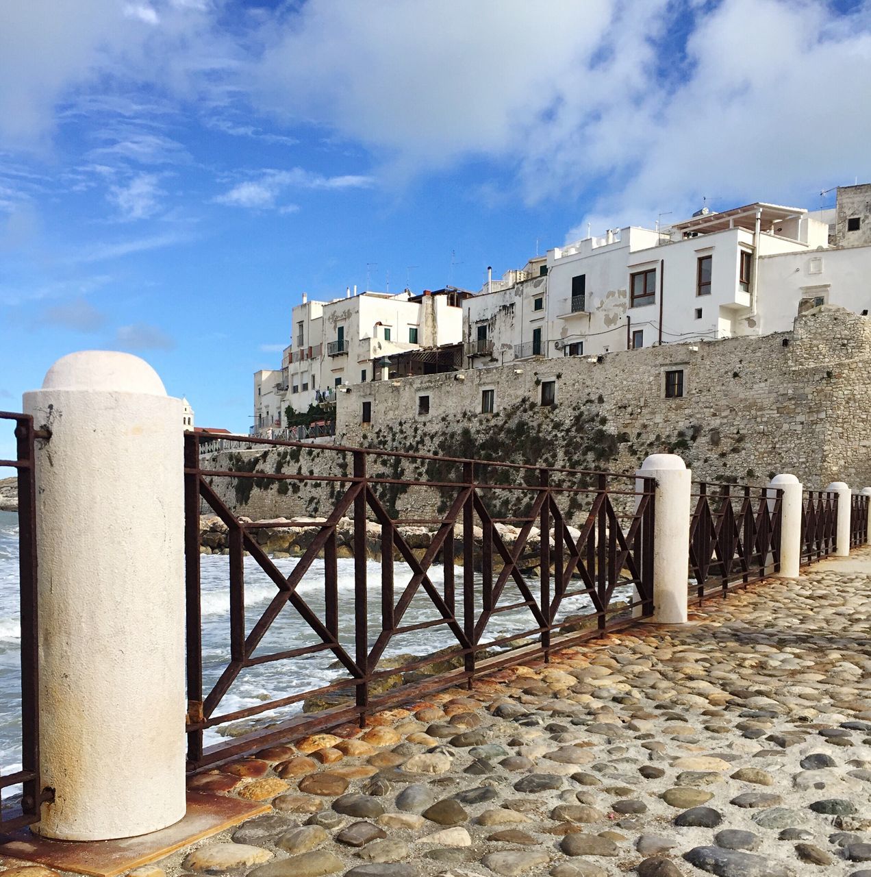 architecture, built structure, building exterior, sky, shore, day, water, in a row, outdoors, history, town, surface level, cloud - sky, footpath, medieval, exterior