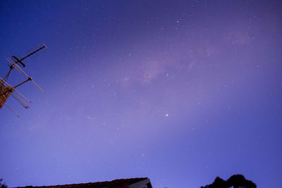 Low angle view of silhouette trees against blue sky at night