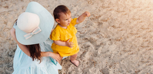 High angle view of mother with baby girl on sand