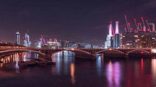 Illuminated bridge over river against sky at night