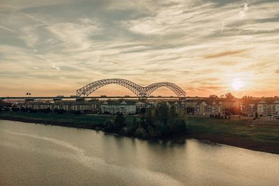 Arch bridge over river during sunset