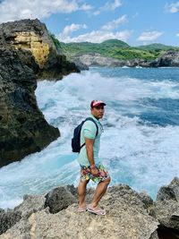 Full length of man standing on rock at sea shore