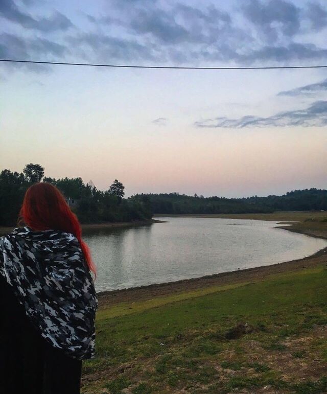 rear view, sky, water, one person, nature, real people, lake, outdoors, cloud - sky, women, beauty in nature, lifestyles, leisure activity, tranquil scene, tranquility, scenics, day, standing, tree, grass, adult, people