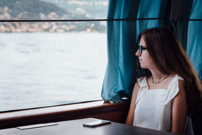 Woman sitting in ferry boat looking through window