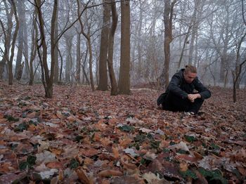 Depressed man sitting on fallen leaves during autumn in forest