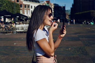 Side view of a smiling young woman in city