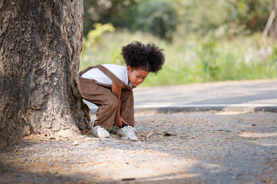 Boy on tree trunk against plants