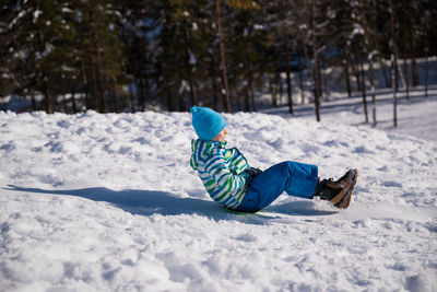 Side view of boy on snow covered land