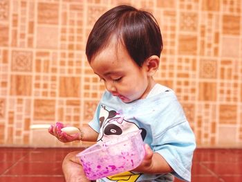 Cute girl holding toy while sitting on brick wall