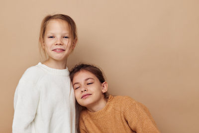 Portrait of smiling sibling against beige background