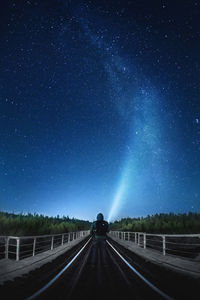 Rear view of person standing on road against starry sky at night